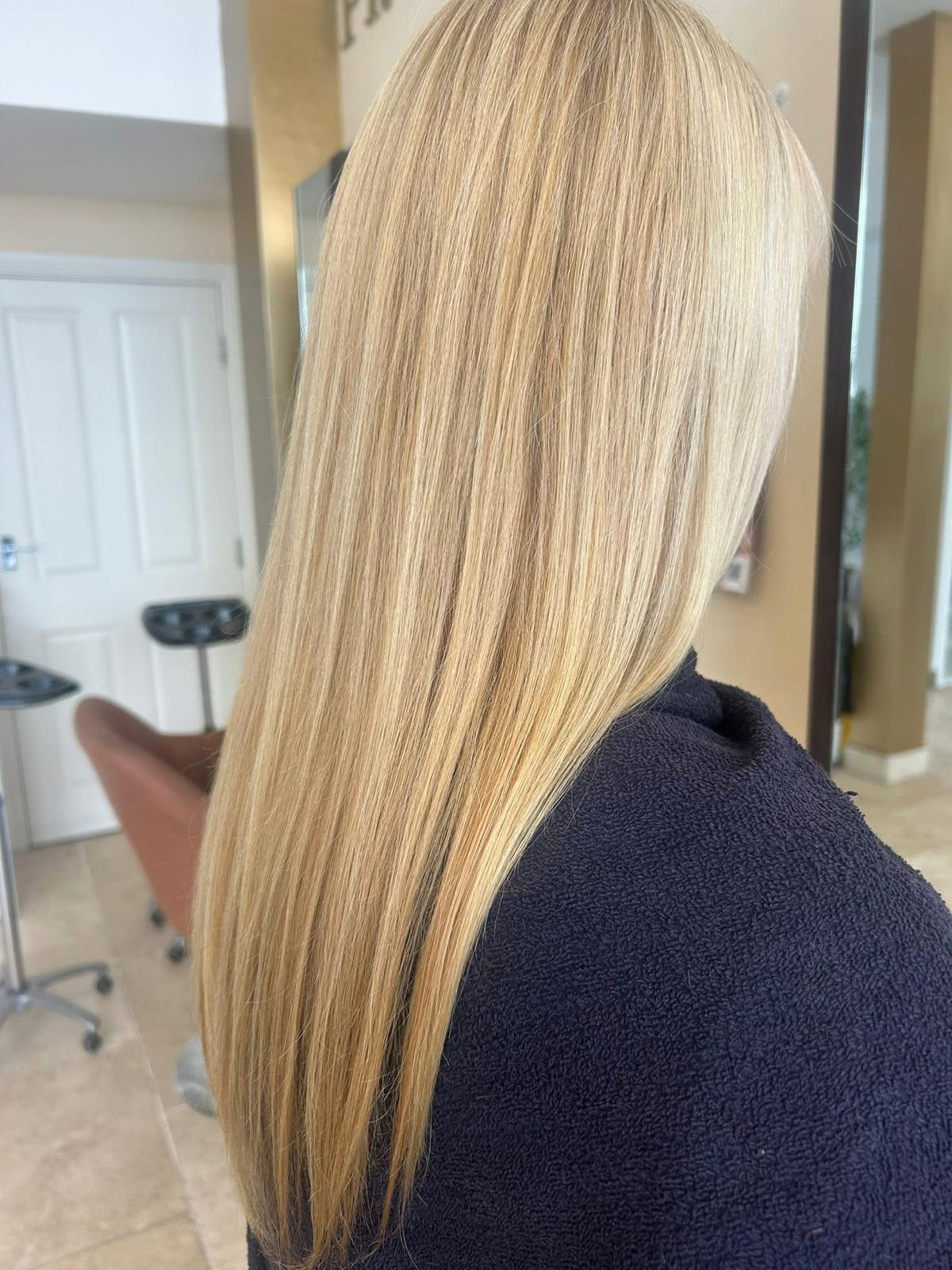 A client's long, glossy blonde hair in the quiet salon at The Color