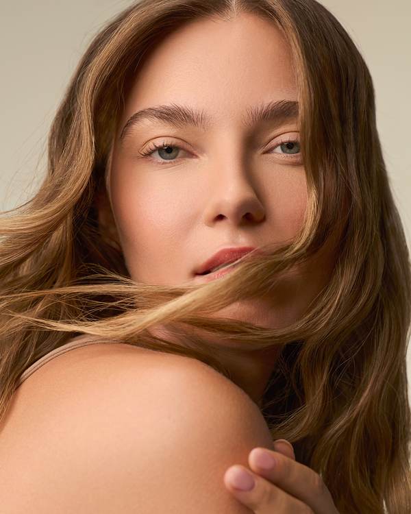 Model with long, honey-brown waves blowing across her face — Paul Mitchell Classic