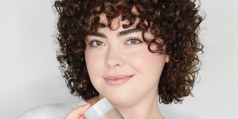 Smiling model with short, dark brown curls — Paul Mitchell Classic