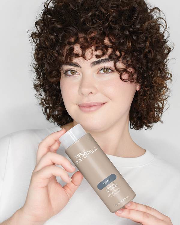 Smiling model with short, dark brown curls — Paul Mitchell Classic