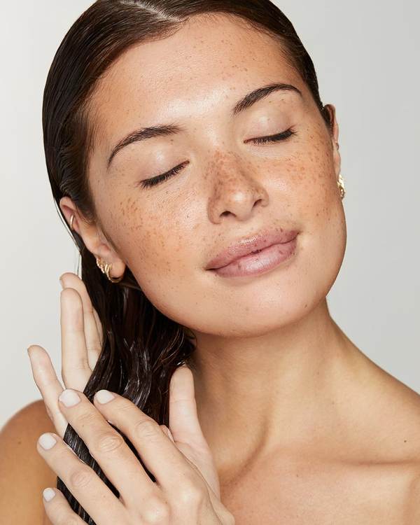 Model with freckles and sleek, wet-look hair, eyes closed — Awapuhi Wild Ginger by Paul Mitchell