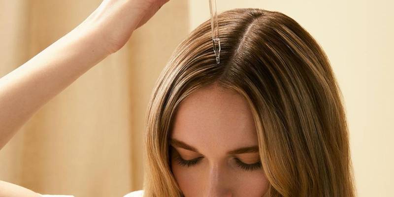 Model applying a serum along her parting with a dropper — Paul Mitchell Tea Tree