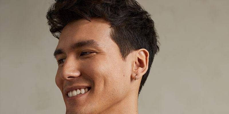 Smiling model with short, textured dark hair — Paul Mitchell Tea Tree Special