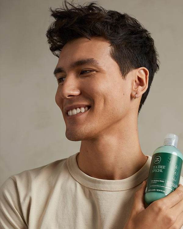 Smiling model with short, textured dark hair — Paul Mitchell Tea Tree Special